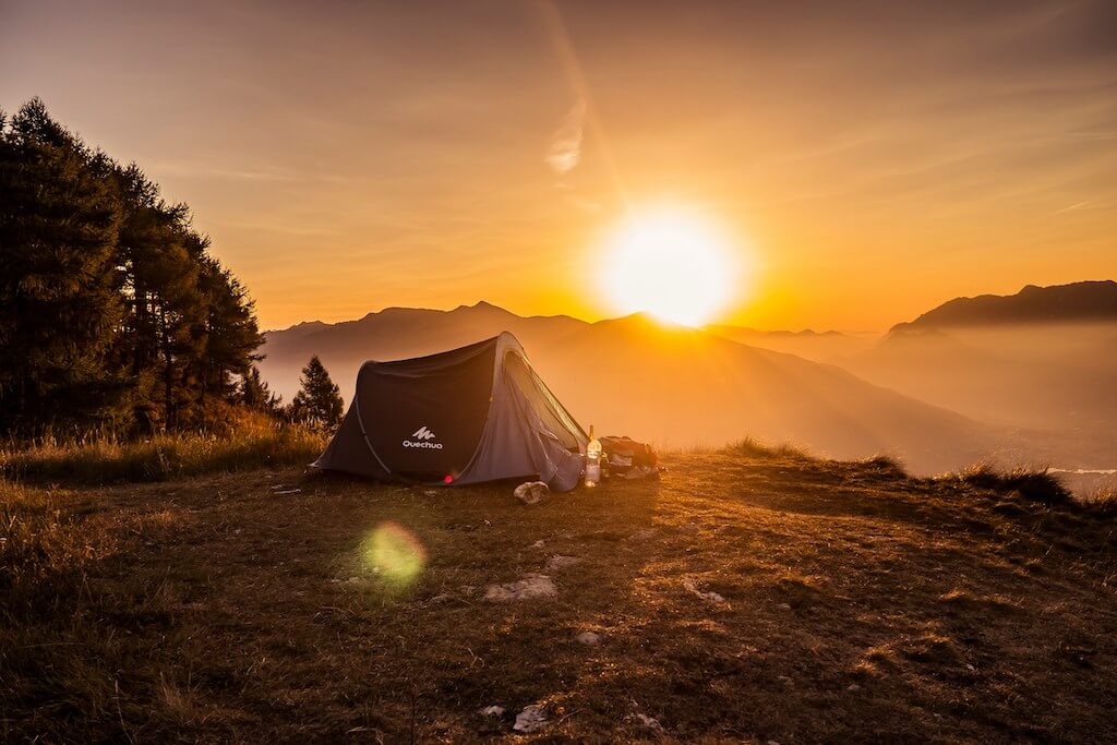 an off-grid camping tent with a rising sun in the background