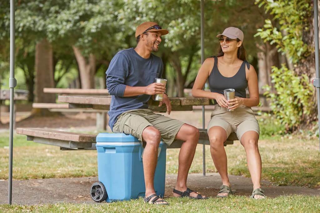 two campers at a picnic table with a cooler