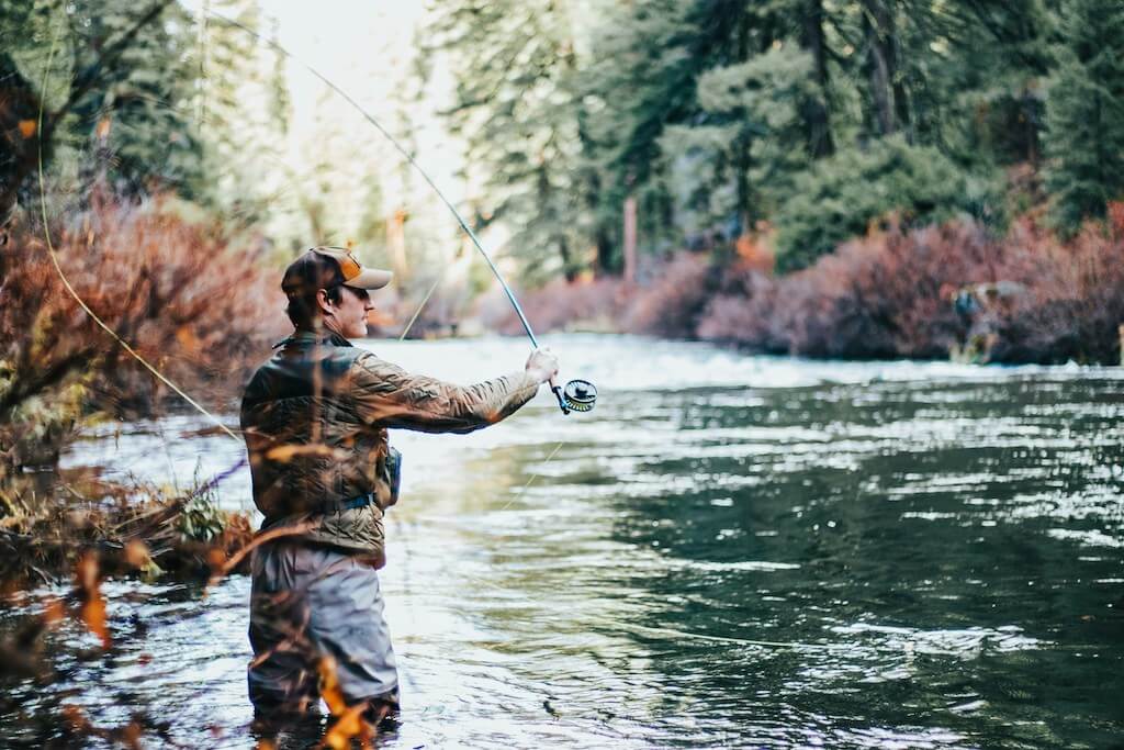 man fly fishing in a river