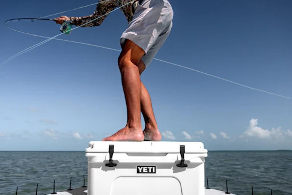 photo of person fishing while standing on camping cooler