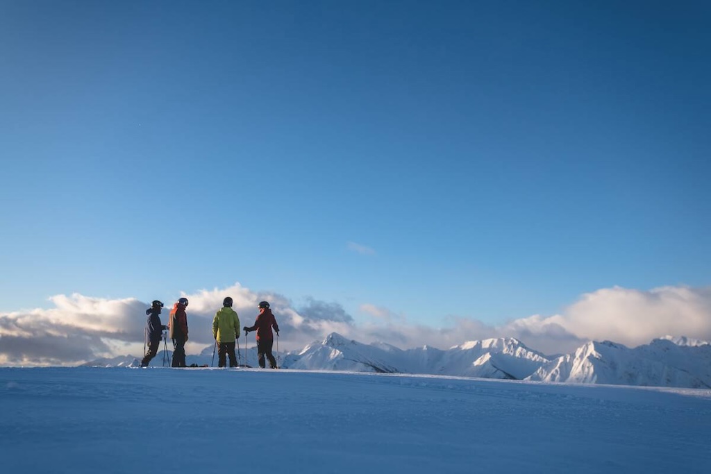 A group of skiers and snowboarders admire the blue sky conditions at Kicking Horse Mountain Resort (Destination BC/Reuben Krabbe)