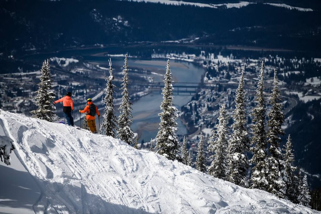 A pair of skiers look down to the town of Revelstoke and Columbia River, from Revelstoke Mountain Resort.